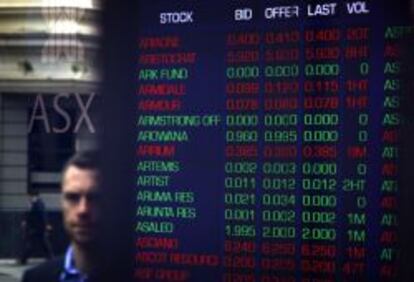 Un peaton pasa por un monitor de la Australian Securities Exchange en Sydney. 