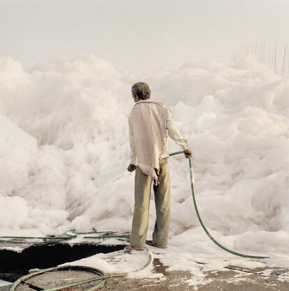 Un trabajador trata de controlar con una manguera la espuma que se genera en aguas del Yamuna