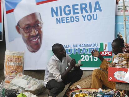 Dos vendedores junto a un cartel promocional del presidente nigeriano Buhari.