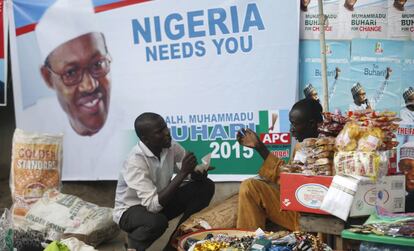 Dos vendedores junto a un cartel promocional del presidente nigeriano Buhari.