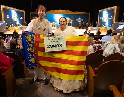 Una pareja vestidos con el traje de fallera y una bandera de la Comunidad Valenciana.