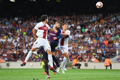 Gerard Piqué remata de cabeza entre dos jugadores del Huesca.