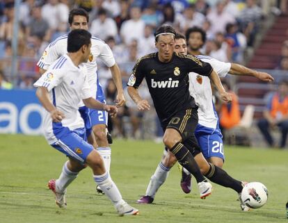 El jugador del Real Madrid, Özil, se intenta ir con el balón entre tres jugadores del Zaragoza.