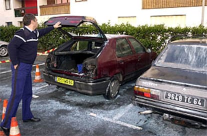 Un gendarme inspecciona los coches quemados esta madrugada en San Juan de Luz.