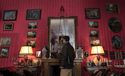 Un hombre observa los cuadros de uno de los salones de la vivienda.