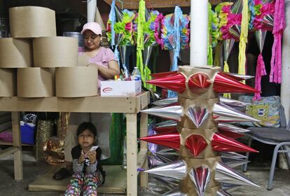 Yolanda Morales hace una piñata, mientras su hija de seis años espera sentada en su taller.