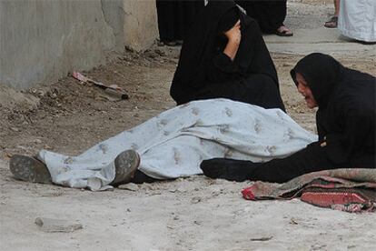 Dos mujeres lloran junto al cadáver del alto oficial del Ejército iraquí tiroteado hoy cuando conducía por Bagdad.