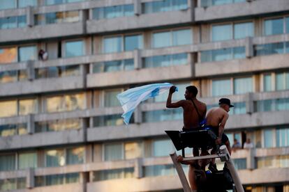 Dos jóvenes treparon el alumbrado público con una bandera argentina, en Buenos Aires.