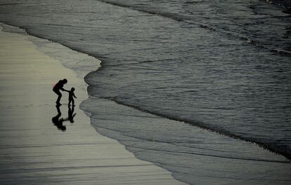 Una mujer sujeta a un niño que quiere alcanzar las olas en la playa de Los Quebrantos en San Juan de la Arena (España), el 7 de noviembre de 2015.