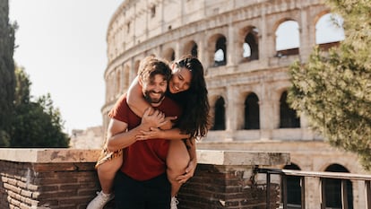 Una pareja bromea con el Coliseo de Roma en el fondo.