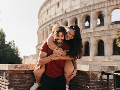 Una pareja bromea con el Coliseo de Roma en el fondo.