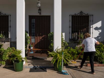 Concha Pérez, vecina de El Garrobo (Sevilla), barre en la puerta de su casa.