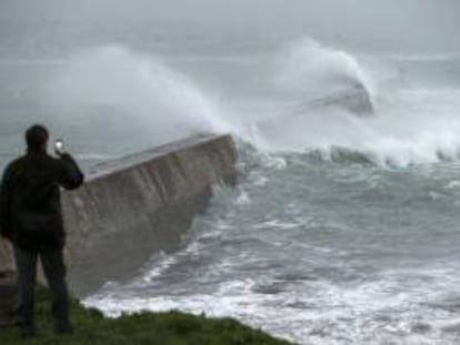 Un hombre fotografía las grandes olas que rompen en un muelle en Esquibien, en la zona oeste de Bretaña, Francia.