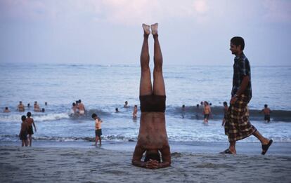 Un hombre practica una postura de yoga en la playa de Fort Cochin.