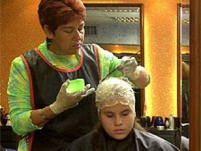 Una peluquera tiñe el pelo a una mujer en una peluquería de Caracas (Venezuela).
