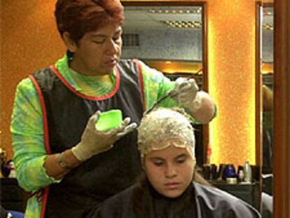 Una peluquera tiñe el pelo a una mujer en una peluquería de Caracas (Venezuela).