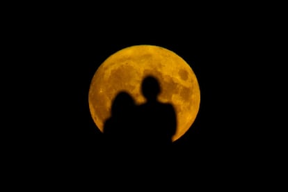 Dos personas miran la superluna salir en Londres (Reino Unido), este jueves.