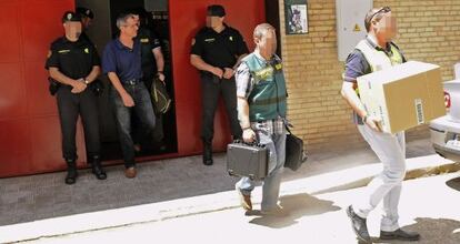 La guardia civil conduce este martes al coche policial a uno de los detenidos durante el registro de la imprenta Lienzo Gr&aacute;fico.