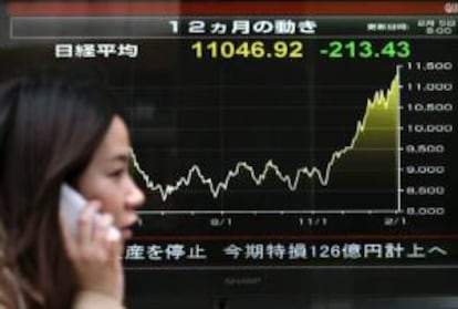 Una viandante camina junto a una pantalla que muestra los datos del cierre de la Bolsa de Tokio.