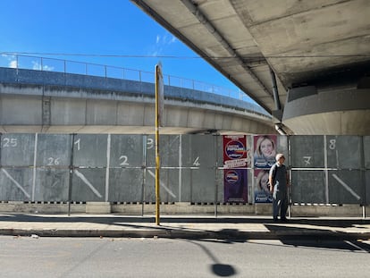 Un hombre espera el autobús ante uno de los carteles electorales de Giorgia Meloni en Ancona.