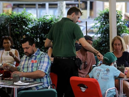 Un cambrer serveix a diverses taules en una terrassa de Barcelona