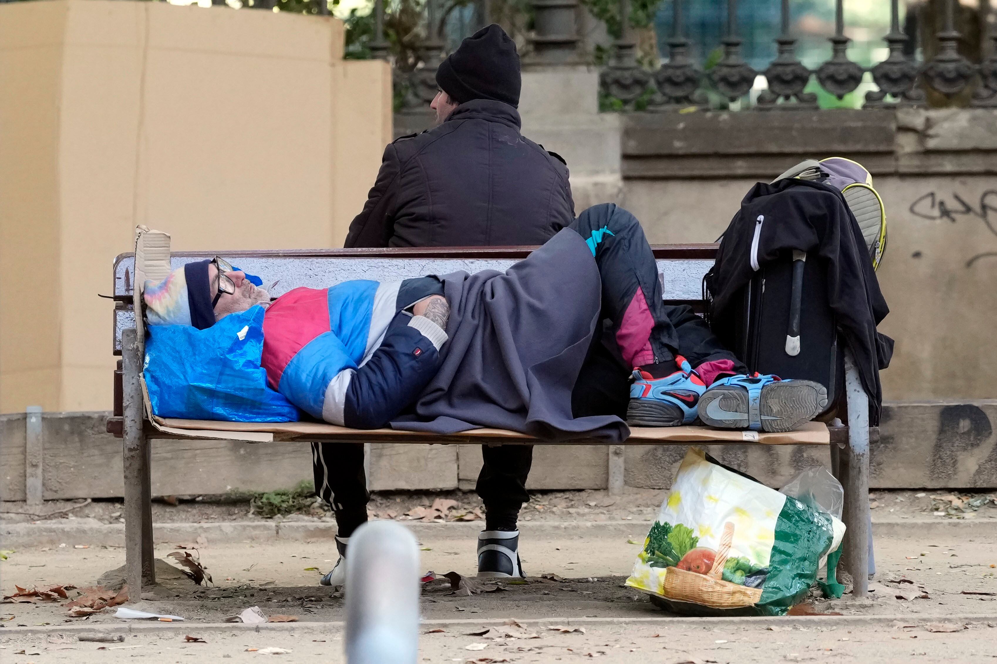 Dos personas sin hogar en un parque de Barcelona.