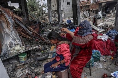 Una mujer palestina cepilla el pelo a una niña, junto algunas de las pertenencias que han podido recuperar entre la destrucción, en la ciudad de Khuzaa, cerca de Jan Yunis, este lunes.