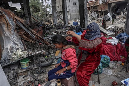 Una mujer palestina cepilla el pelo a una niña, junto algunas de las pertenencias que han podido recuperar entre la destrucción, en la ciudad de Khuzaa, cerca de Jan Yunis, este lunes.  