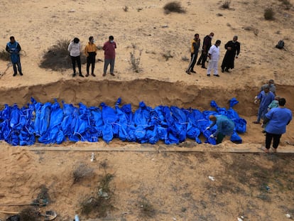 Un grupo de operarios entierra decenas de cadáveres en una fosa común en el cementerio de Jan Yunis, en el sur de Gaza, el 22 de noviembre.