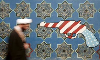 Un clérigo iraní pasa junto a un mural en la pared de la antigua embajada de Estados Unidos en Teherán, Irán.