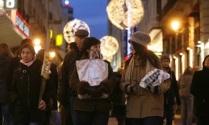 Ciudadanos cargados con regalos hacen sus compras de Navidad, en la calle Preciados de Madrid.