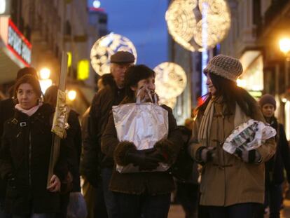 Ciudadanos cargados con regalos hacen sus compras de Navidad, en la calle Preciados de Madrid.