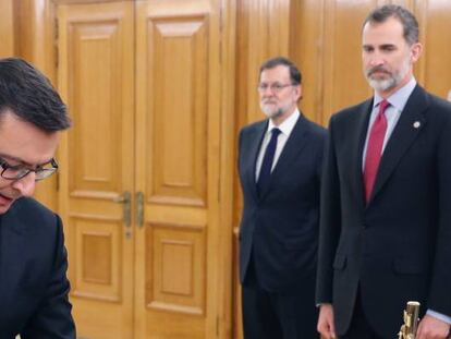 El nuevo ministro de Economía, Román Escolano (izquierda), jura su cargo ante el Rey Felipe VI (derecha) en el Palacio de la Zarzuela de Madrid, en presencia del presidente del Gobierno, Mariano Rajoy.