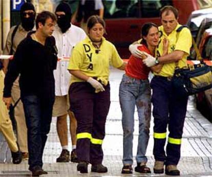 Una de las mujeres que ocupaban el coche donde se produjo el estallido es consolada por miembros de la DYA.