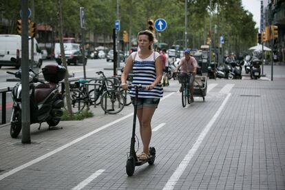 Una mujer circula con un patinete eléctrico por el carril bici de la acera de la Gran Via de Barcelona.