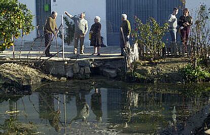 Vecinos y curiosos, junto a la acequia en la que supuestamente cayó un objeto.