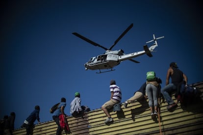 Un grupo de migrantes centroamericanos trepa la valla fronteriza entre México y Estados Unidos, cerca del cruce fronterizo de El Chaparral, en Tijuana.