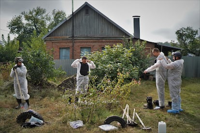 Un grupo de trabajadores se prepara antes de comenzar a desenterrar cuerpos el sábado en Izium.