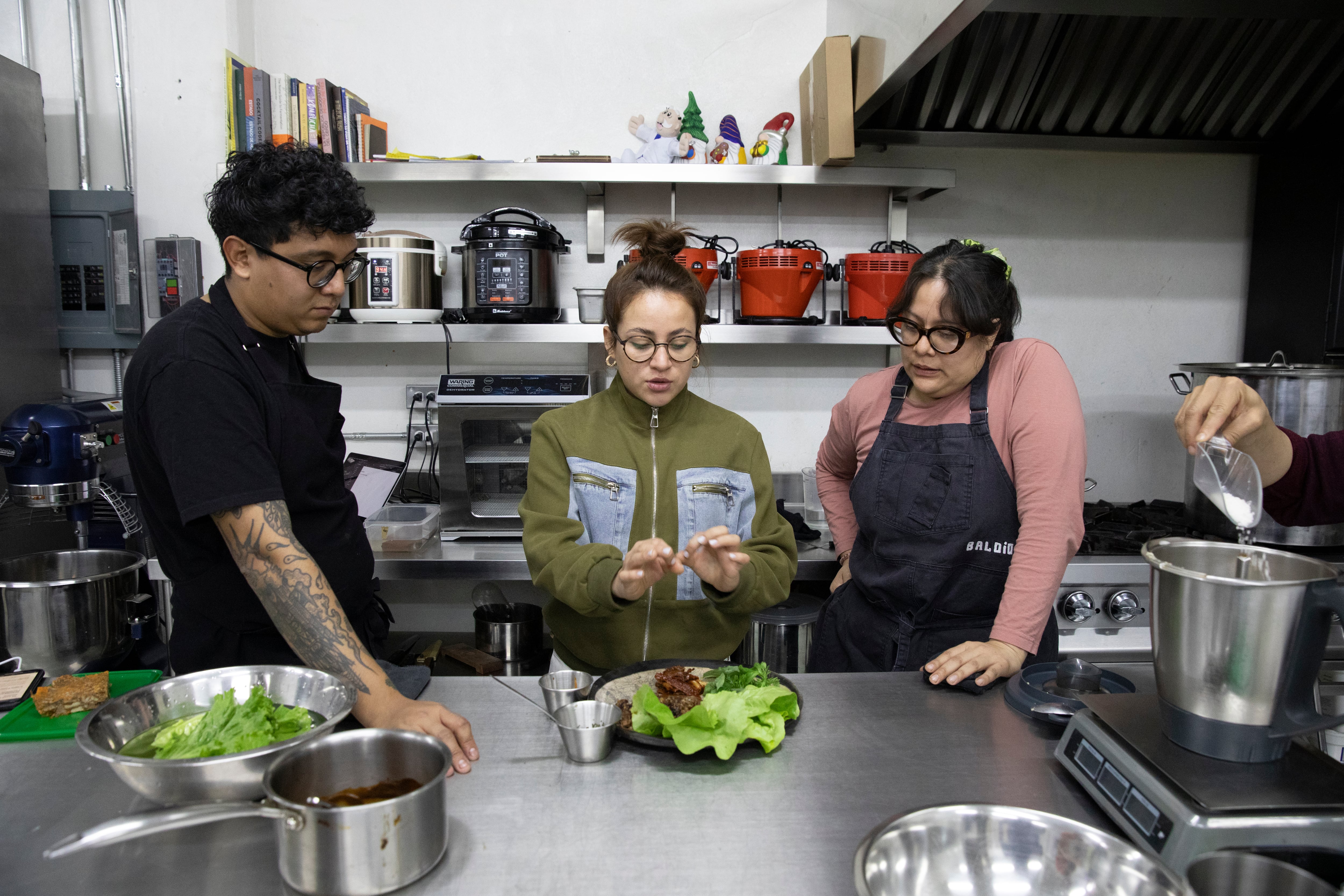 Daniel Vidal, líder de desarrollo de menús; Vanessa García, coordinadora de procesos y estándares culinarios y Laura Cabrera Hernández, chef, prueban los nuevos tacos de cerdo con mole de tamarindo en el Baldega (taller de Baldío).