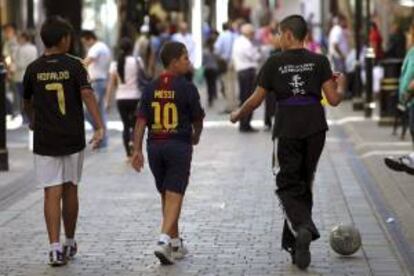 Tres ni?os con camisetas de ftbol caminan por la calle de Main Street en Gibraltar (Reino Unido).