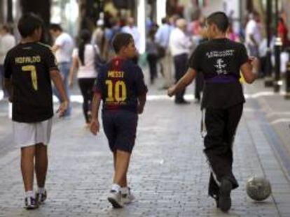 Tres niños con camisetas de fútbol caminan por la calle de Main Street en Gibraltar (Reino Unido).