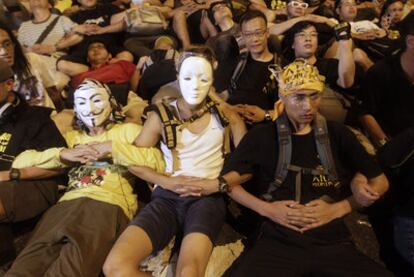 Manifestantes, sentados, con los brazos unidos y con máscaras, en una protesta en Hong Kong.