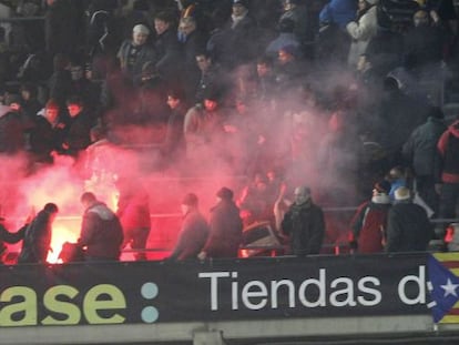 Aficionados del Madrid reciben una bengala lanzada por los del Barça, el 26 de febrero en el Camp Nou