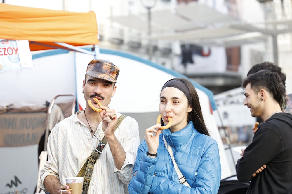 Dos personas acampadas en Sol desayunan, este domingo.