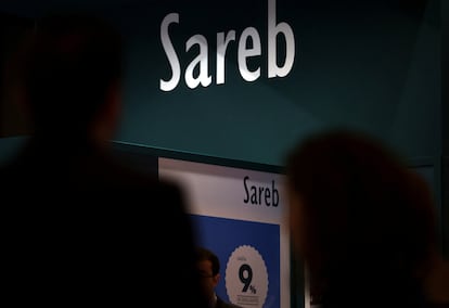 Varias personas pasan ante un anuncio de venta de viviendas de la Sareb, en una imagen de archivo.