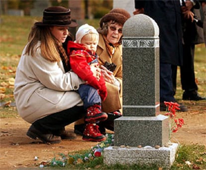 Nina Schleifer sujeta a su niña Tiia, junto a su abuela Magda, ante la tumba del <i>niño desconocido</i> que ha resultado ser su pariente.