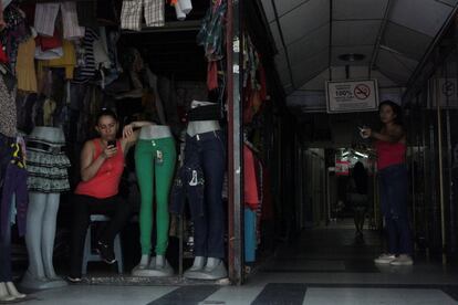 Duas comerciantes aguardam em suas barracas no escuro em San Cristóbal, no oeste do país, na terça-feira. Algumas áreas de outro estado ocidental, Zulia, acumularam 31 horas sem eletricidade desde o apagão de segunda-feira.