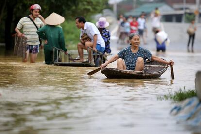 Una mujer cruza una avenida en barca en la comunidad de Hoang Van Thu, Hanoi (Vietnam).