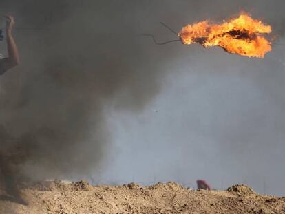Un palestino lanza un neumático en llamas contra las tropas israelíes.