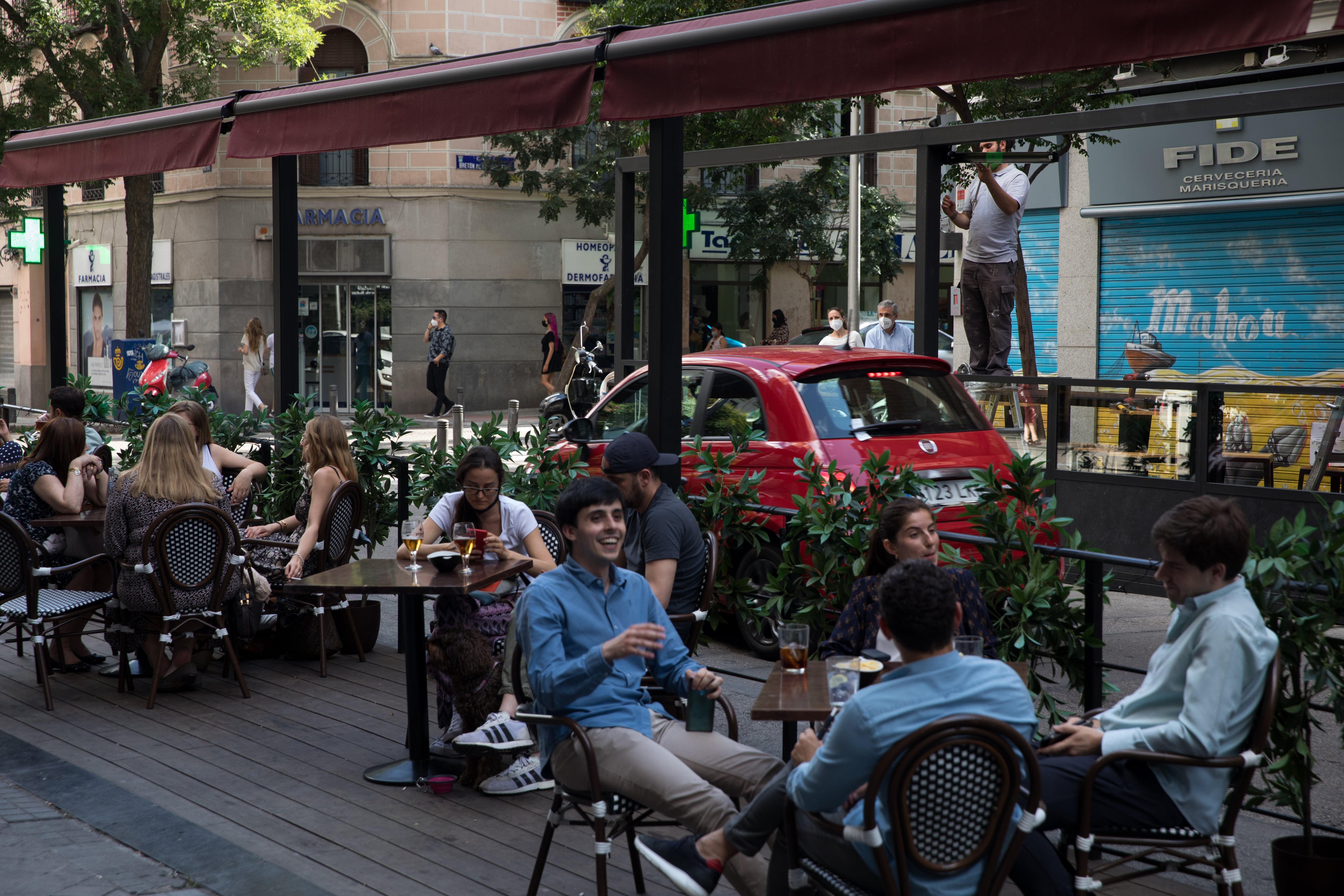 Unos operarios instalan un toldo en una terraza puesta en plazas de aparcamiento en la calle Ponzano de Madrid, el 3 de junio de 2021.
